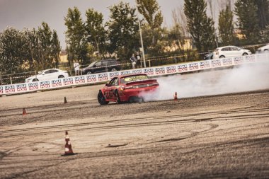 Villamarzana, Italy 17 September 2024: A red Nissan performs an intense drift on the track, tires smoking and the driver in control. clipart