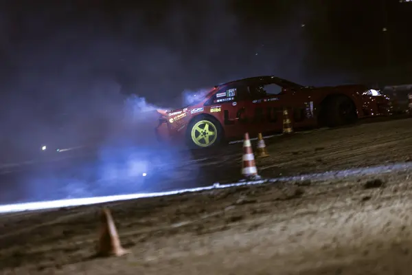 stock image Villamarzana, Italy 17 September 2024: A red drift car slides at night, sparking with rear wheels lit up, racing on a track with smoke effects.