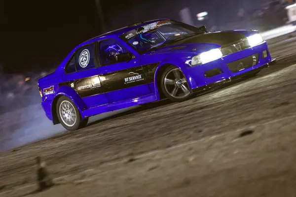 stock image Villamarzana, Italy 17 September 2024: A blue drift car takes a sharp turn on the track at a night event, drifting around traffic cones with precision.