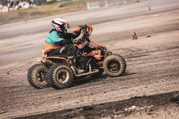 Villamarzana, İtalya 17 Eylül 2024: Turuncu bir ATV üzerindeki bir sürücü bir off-road etkinliği sırasında engebeli, açık bir pistte sürükleniyor.