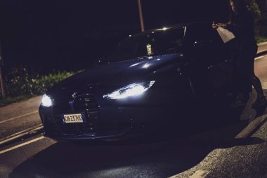 Milan, İtalya 4 Ekim 2024: Bir sürücü gece yol kenarında arabasının yanındaki haritayı kontrol ediyor