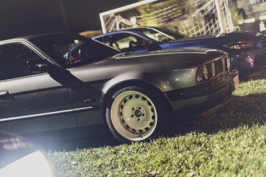 Milan, İtalya 4 Ekim 2024: Gri, eski bir Alman arabası arka planda diğer arabalarla birlikte geceleyin çimlerin üzerine park edildi