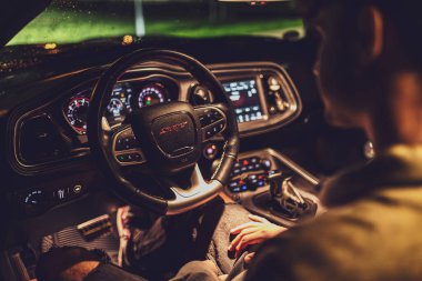 Milan, İtalya 4 Ekim 2024: Bir çift modern bir arabanın ön koltuklarında otururken el ele tutuşuyor