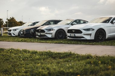 Milan, İtalya 4 Ekim 2024: Bulutlu bir günde modern arabalar peş peşe park edilmiş, parlak tasarımlarını ve güçlü varlıklarını sergiliyorlar