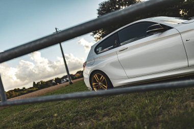 Milan, İtalya 4 Ekim 2024: Altın jantlı beyaz bir spor araba çimen tarlasına park edildi