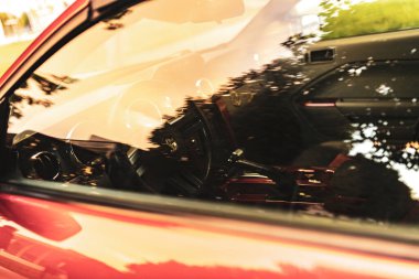 Milan, İtalya 4 Ekim 2024: Kırmızı bir spor arabanın gösterge panelinden ve direksiyonundan yansıyan güneş ışığı