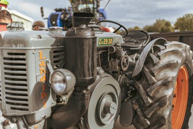 Milan, İtalya 8 Ekim 2024: Arka planda tarımsal bir sergide konuşan bulanık mekanikli gri bir traktör motorunun yakın çekimi