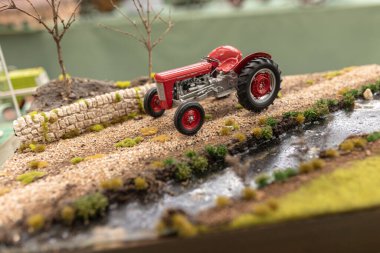 Milan, İtalya 8 Ekim 2024: Minyatür bir kırmızı traktör, tarımsal hayatın detaylarını gösteren bir minyatür çiftliğe park edilmiştir.