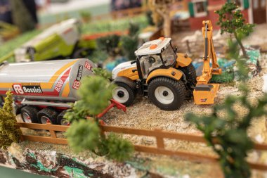 Milan, Italy 8 October 2024: Miniature farm scene showcasing toy tractors and agricultural vehicles, highlighting the details of modern farming equipment clipart