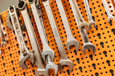 Milan, İtalya 8 Ekim 2024: Bir tamirci atölyede parlak turuncu bir tahta üzerinde farklı boyutlarda krom anahtarlar düzenliyor