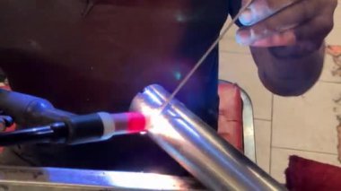 Kaynakçı, tungsten inert gaz (tig) kaynak tekniğini kullanarak iki metal boruya bağlanır.