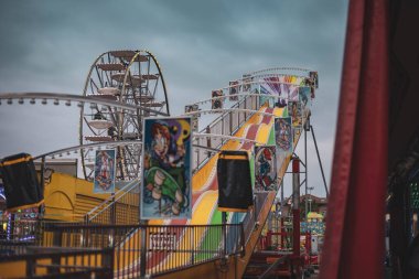 Rovigo, İtalya 24 Ekim 2024: Dev bir kaydırak ve dönme dolap, eğlence parkı heyecanı için büyüleyici bir manzara yaratıyor.