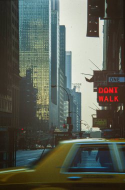 New York, ABD 1975 Mayıs: 1970 'lerde yoğun bir New York caddesinde, neon ve yüksek binaların önünden geçen sarı taksi