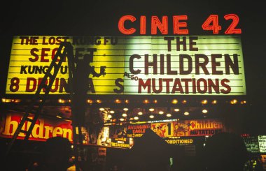 New York, ABD 1975 Mayıs: İşçi 1975 'te Times Square, New York' ta gece yarısı ilan panosunda film başlıklarını değiştirdi