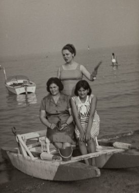 Roma, İtalya 1964: Üç kadın bir pedal teknesinde oturuyor. Kumsalda güneşli bir günün tadını çıkarıyorum. Arka planda klasik bir motorlu tekne var.