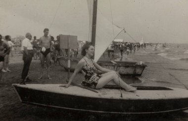 Roma, İtalya 1964: 20. yüzyılın ortalarında kıyıya vurmuş bir yelkenlide dinlenen zarif bir kadının klasik fotoğrafı.