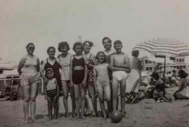 Roma, İtalya 1964: Aileler güneşli bir sahilde güneşli bir günün tadını çıkarırken, mayo giymiş eski bir fotoğrafa poz veriyorlar