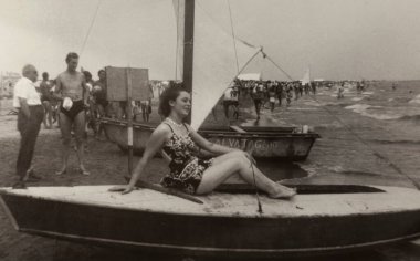Roma, İtalya 1964: 1960 ya da 1970 'lerde muhtemelen kalabalık bir plajda küçük bir yelkenlide dinlenen bir kadının klasik siyah beyaz fotoğrafı