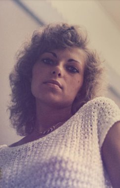 Roma, İtalya 1964: Beyaz örgülü bluz ve kolye giyen kıvırcık saçlı kadın 1970 'lerdeki moda ve güzellik eğilimlerini anımsatıyor.