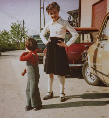 Roma, İtalya 1964: 70 'lerin güneşli bir gününde, elleri kalçasında gülümseyen bir kızın, yeni yürümeye başlayan bir çocuğun ve klasik arabaların yanında poz verdiği klasik fotoğraf