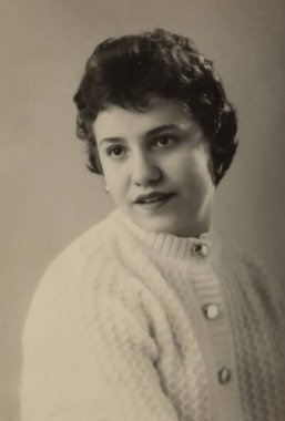 Roma, İtalya 1964: Beyaz hırka giyen ve kameraya bakmayan gülümseyen genç bir kadının stüdyo portresi