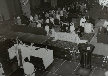 Roma, İtalya 1964 'te olabilir: Bir rahibin kilisede nikah törenini kutlarken çekilmiş siyah beyaz fotoğrafı, gelin, damat, misafir ve çiçekçi kızlarla birlikte.