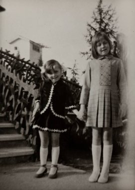 Roma, İtalya 1964 olabilir: 1960 'ların modasına uygun giyinmiş iki genç kız, bir bahçede el ele tutuşup gülümsüyor, iç açıcı bir klasik sahne yaratıyor