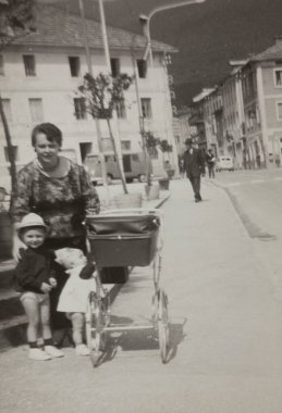 Roma, İtalya 1964: İki çocuğu ve bir bebek arabasıyla 1960 'ların kentsel ortamında kaldırımda gezinen bir anneyi canlandıran klasik siyah beyaz fotoğraf