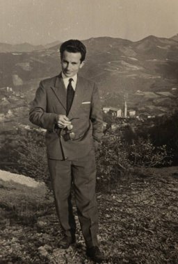 Roma, İtalya 1964 'te olabilir: Güneş gözlüğü tutan bir işadamının klasik portresi, 20. yüzyılın ortalarında pitoresk bir dağ zeminine karşı poz verdi