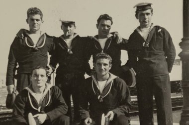 Rome, Italy may 1964: Six cheerful sailors in uniform are posing for a group photo, some holding their hats and one smoking a cigarette, in a vintage snapshot from the mid-20th century clipart