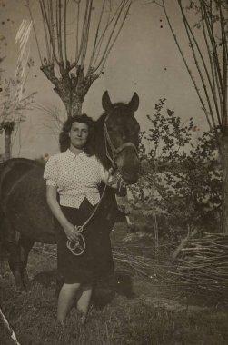 Roma, İtalya 1965 olabilir: Sepia tonlu eski fotoğraf, sakin bir kırsal alanda atının yanında gururla duran genç bir kadını daha basit zamanlar için nostalji duygusunu anımsatır.