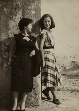 Roma, İtalya 1965 olabilir: 1960 'larda elbise giyen iki kadın fotoğraf için poz veriyor, biri gülümsüyor ve ekose etek giyiyor