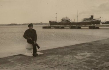 Roma, İtalya 1965 olabilir: 1960 ya da 1970 'lerde rıhtımda demirlemiş bir kargo gemisini seyreden bir denizcinin siyah beyaz fotoğrafı.