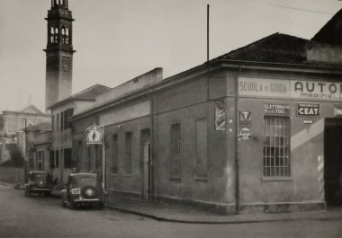 Roma, İtalya 1965 olabilir: 1960 'lardan kalma tarihi mimari ve tabelalar sergilenerek İtalya' daki bir sürücü okulu ve garajının önüne park edilmiş klasik arabalar