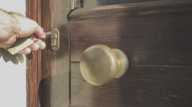 Bir kapıyı anahtarla açıp kilitleme eylemine giren bir adam.