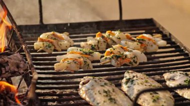 Şef, sıcak ızgarada balık ve kabuklu deniz ürünlerinden oluşan lezzetli bir yemek hazırlıyor.