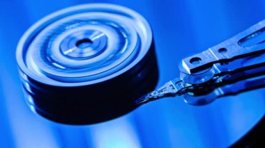 Sabit disk sürücüsü veri kolu oynatma ya da yazma ile birlikte hızla dönüyor. Teknolojik sürecin mavi tonlarda yakın görüntüsü