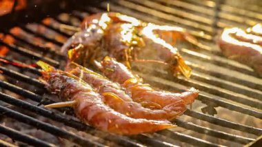 Şef karideslerin üzerine zeytinyağı döker barbeküde ızgara yapar