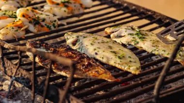 Şef mevsimleri mangalda baharatlı balık ve karides pişiriyor.