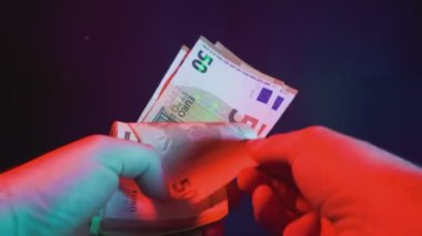 Krupiye parlak renkli ışıkların altında euro banknotlarını ustaca sayıyor.