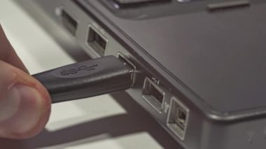 Bilgi transferi için bir USB kablosunu laptopun portuna bağlayan kişi