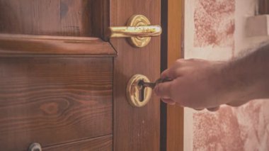 Bir adam tarafından altın saplı ahşap bir kapıyı açmak