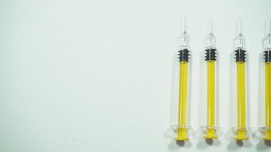 Beyaz arka planda birkaç sarı şırınga var.