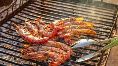 Sıcak kömürlerin üzerinde ızgara yapan lezzetli karides şişleri, dışarıda ızgarada ustalıkla çeviren biri olarak yükselen duman. Mükemmel bir açık hava yemek sahnesi.