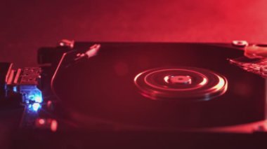 Kırmızı ışıkla aydınlatılan, veri teknolojisi mekanikleri ve karmaşık elektronik bileşenlerle aydınlatılan açık disk sürücüsünün ayrıntılı görünümü