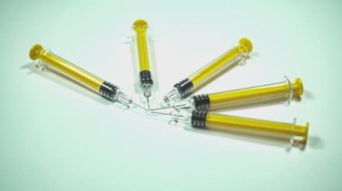 Sarı sıvı içeren birkaç şırınga beyaz arka planda bir çember oluşturuyor.