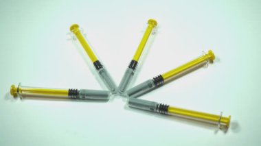 Yedi sarı şırınga dönüyor, hipnotik bir görsel etki yaratıyor.