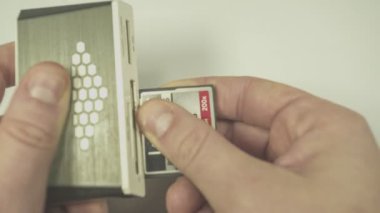 Teknisyen, beyaz arkaplandaki kart okuyucusuna bir SDD kartı yerleştiriyor.