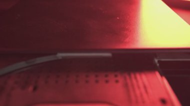 DVD sürücüsü tepsisi açılıp kapanıyor, ürkütücü bir kırmızı ışıkta yıkanıyor.