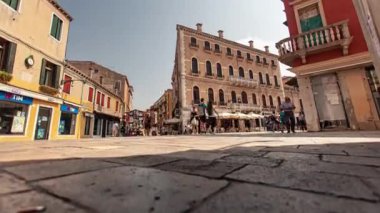 Venedik, İtalya 1 Ocak 2025: Yayalar, açık gökyüzü altındaki tarihi mimari ve renkli binalarla çevrili canlı bir Venedik meydanından geçerek İtalya 'da turizmin özünü yakalıyorlar